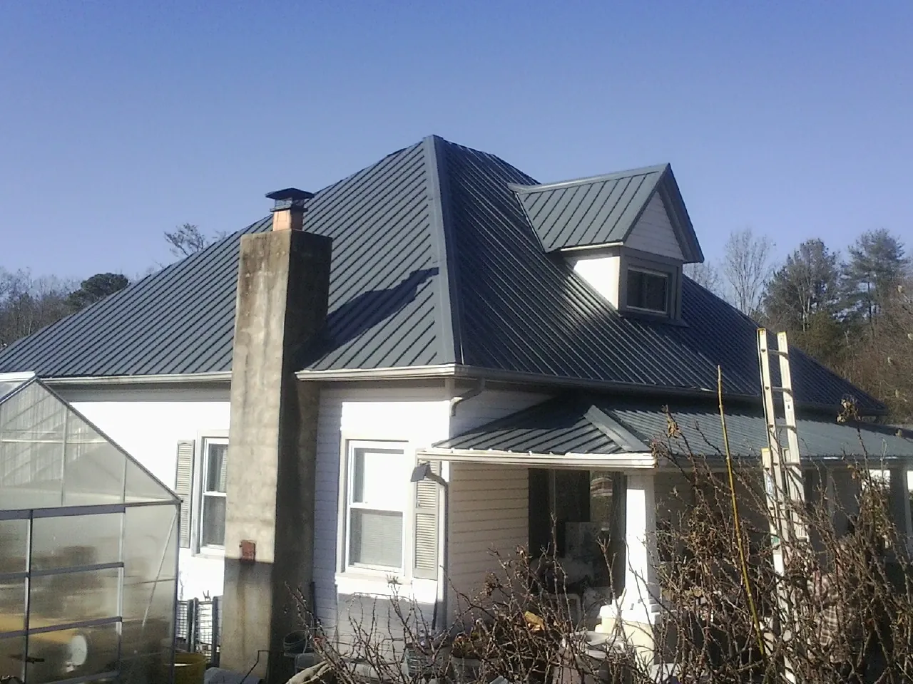 Dark blue standing seam metal roof on a white farmhouse with dormer — Slate & Tile Roof Repair by Roofing Brothers in Jamesport