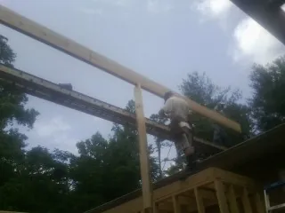 Carpenter setting a ridge beam over a new addition frame — Ice Dam Removal by Roofing Brothers in Jamesport
