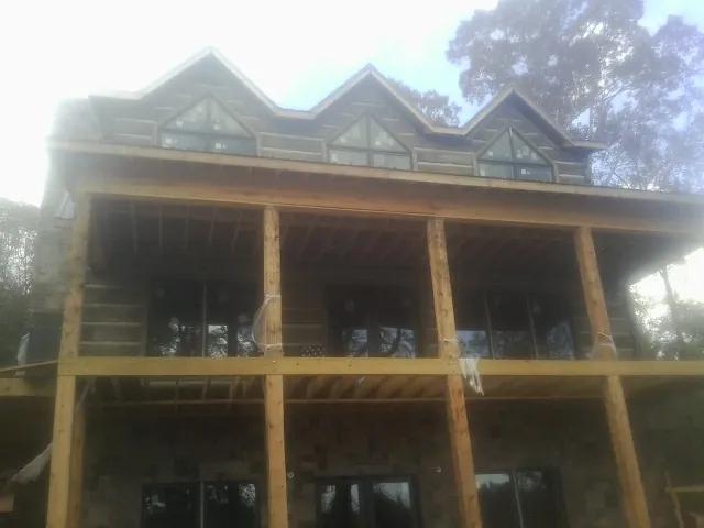Dormers and porch framing on a large log home under construction — Roof Coating work by our crew in Jamesport