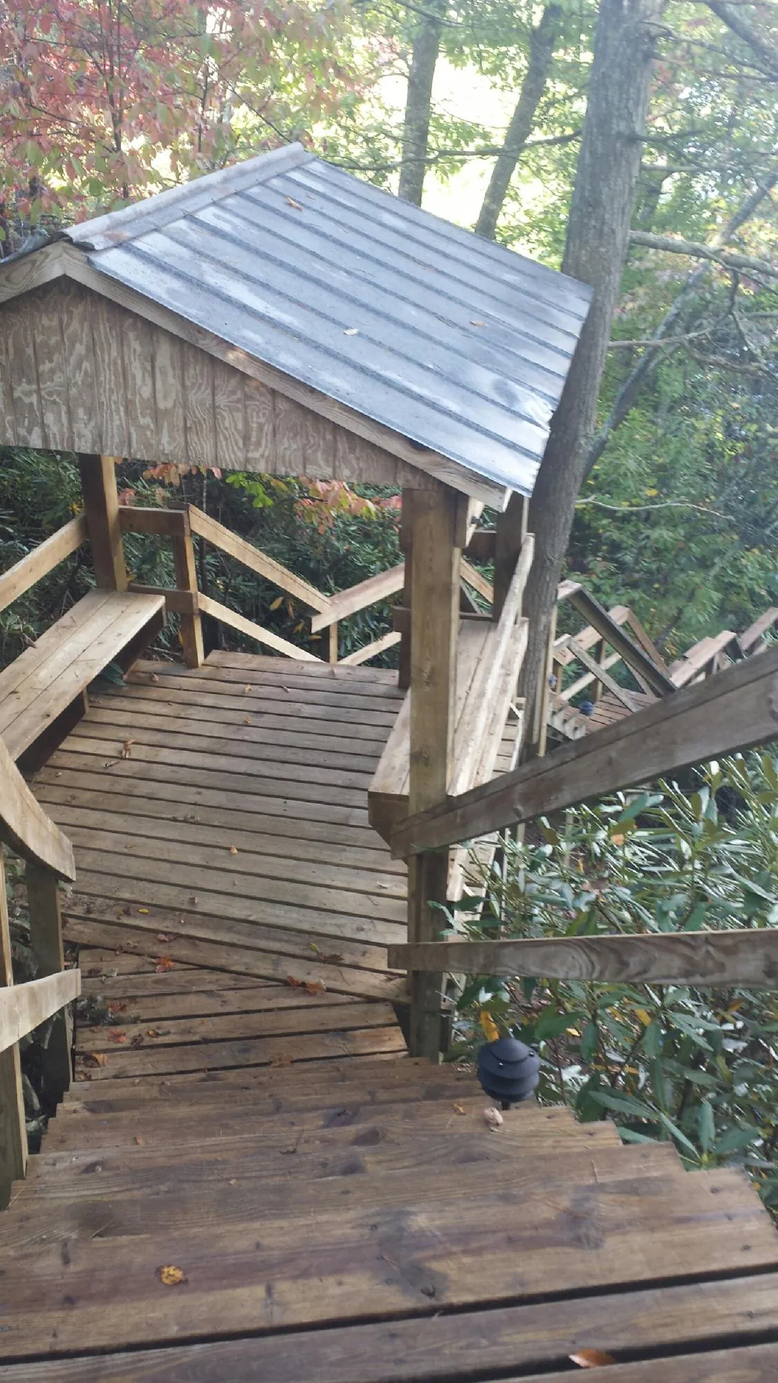 Metal roofed shelter over wooden steps on a wooded walkway — Skylight Repair & Installation work by our crew in Jamesport