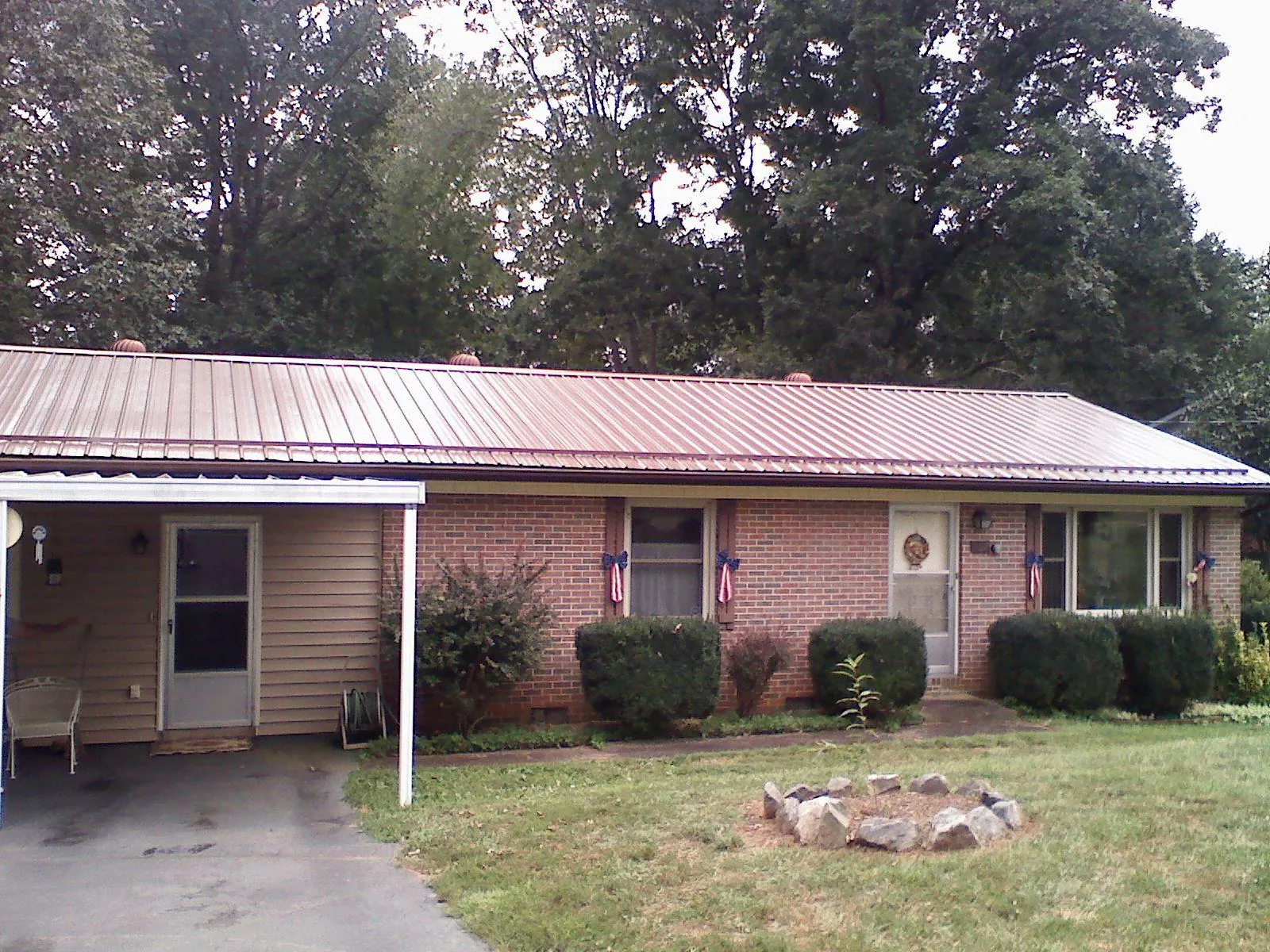 Bronze metal roof and carport on a brick ranch home — Roof Repair work by our crew in Jamesport