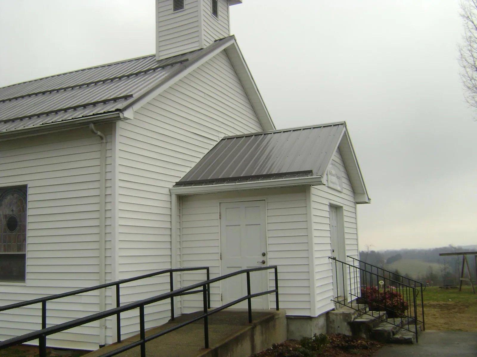 Gray metal roof on a white clapboard church with a steeple in Jamesport