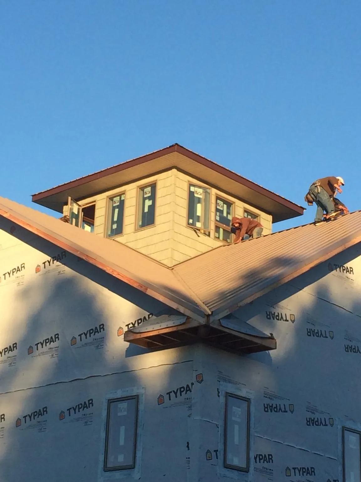 Roofers working around a rooftop cupola on a new metal roof at sunset — Roof Waterproofing in Jamesport by Roofing Brothers